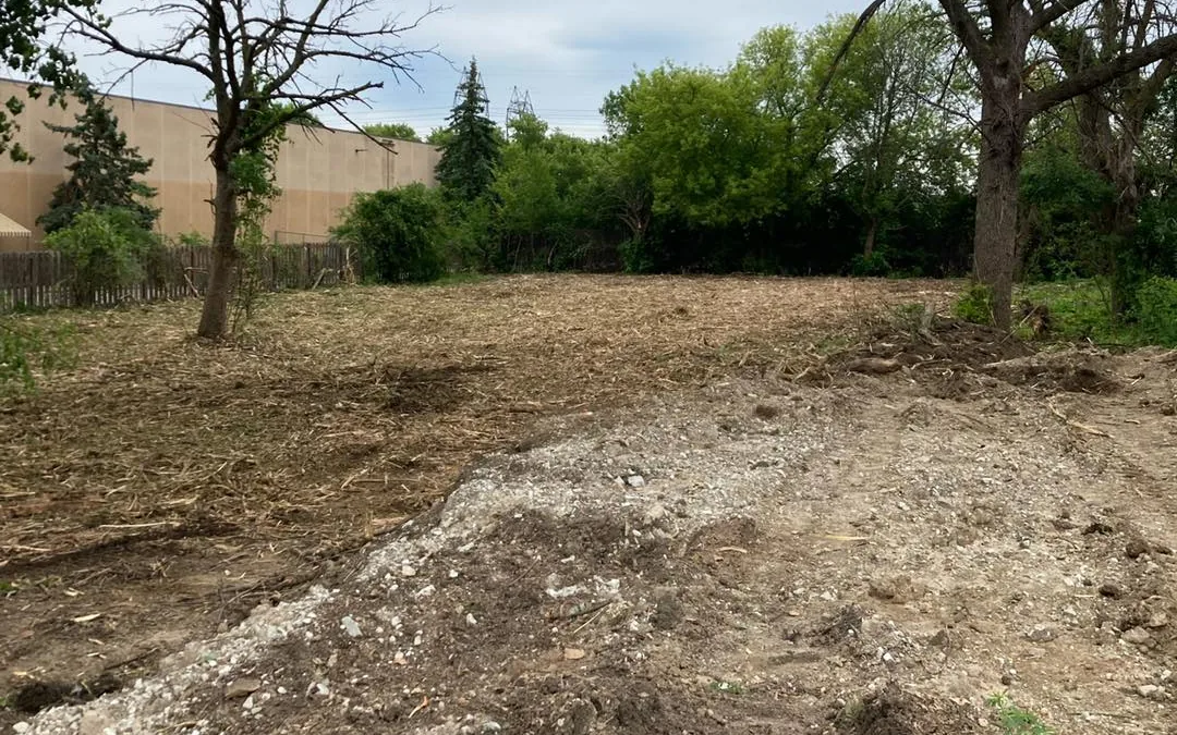 After: the same lot cleared and rough graded beside a commercial building